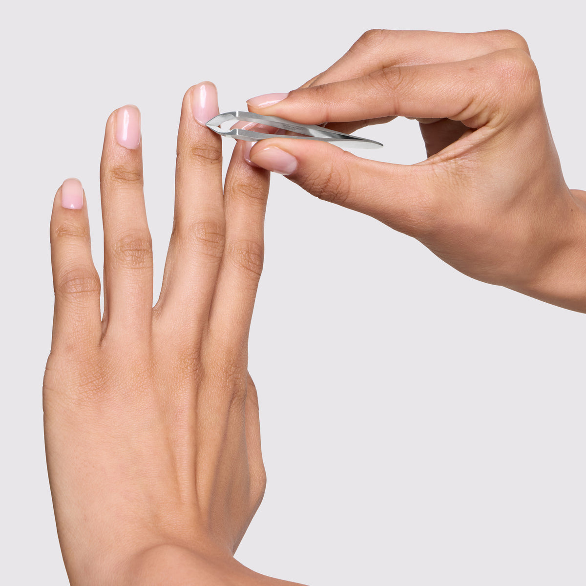 Model is trimming her cuticles with Evening Glow Mini Cuticle Nipper