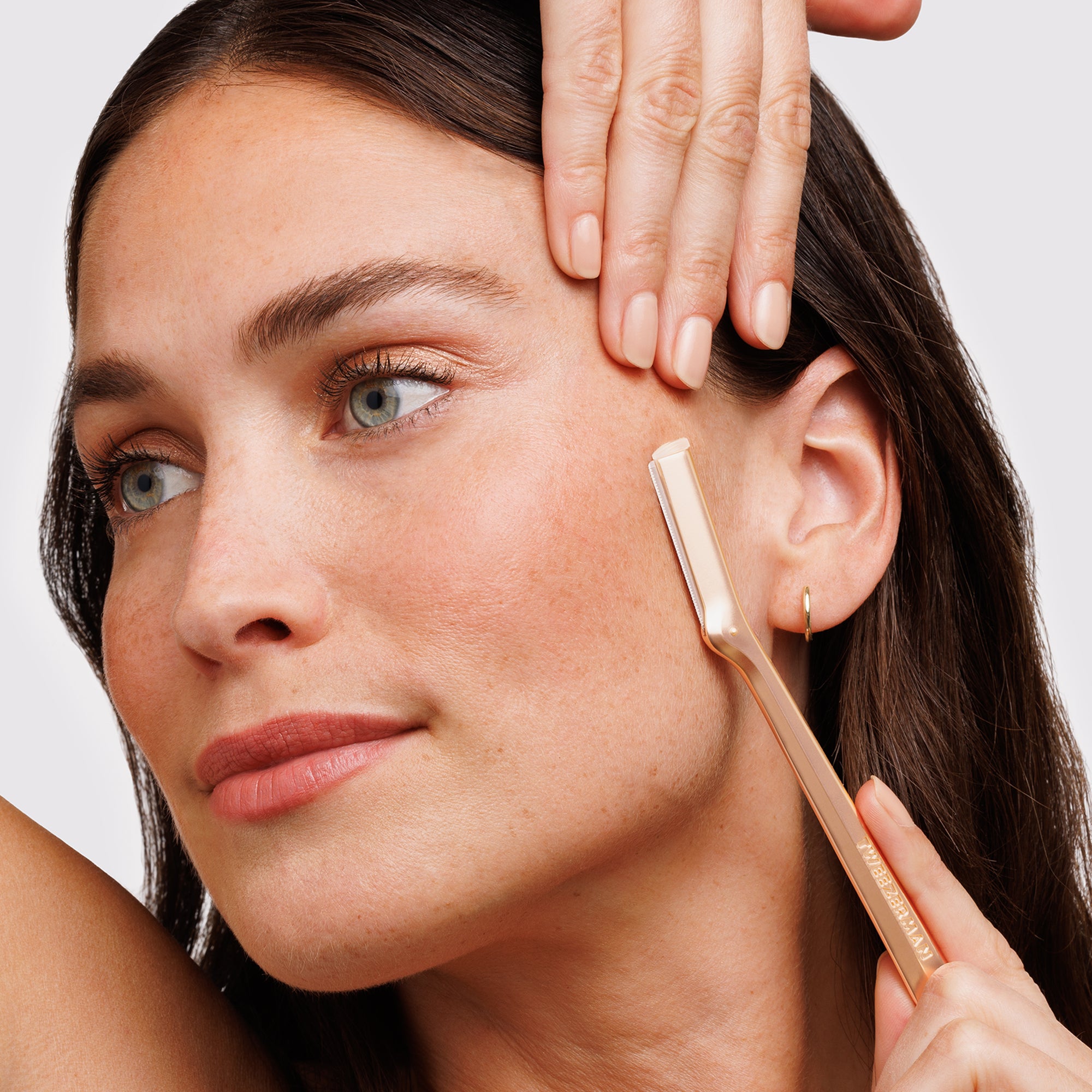 MODEL USING ROSE GOLD FACIAL RAZOR on the side of the face
