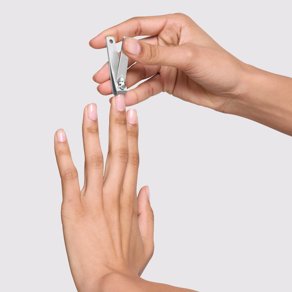 Model is cutting her nails with Evening Glow fingernail clipper