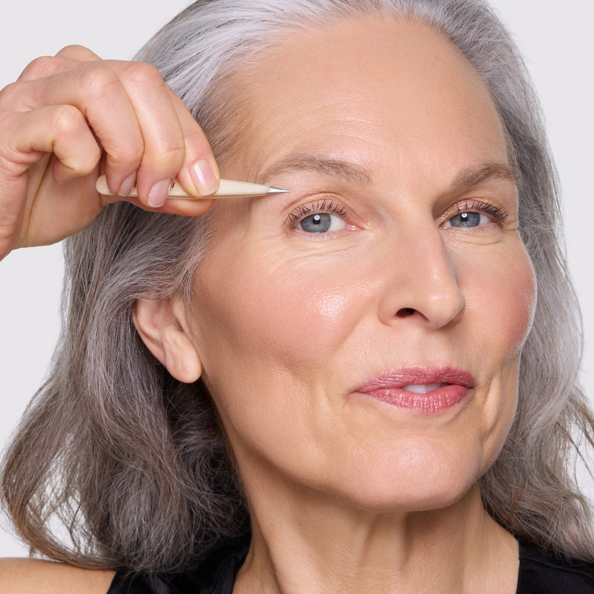 Model is using point tweezer of the Evening Glow Mini Tweezer Set