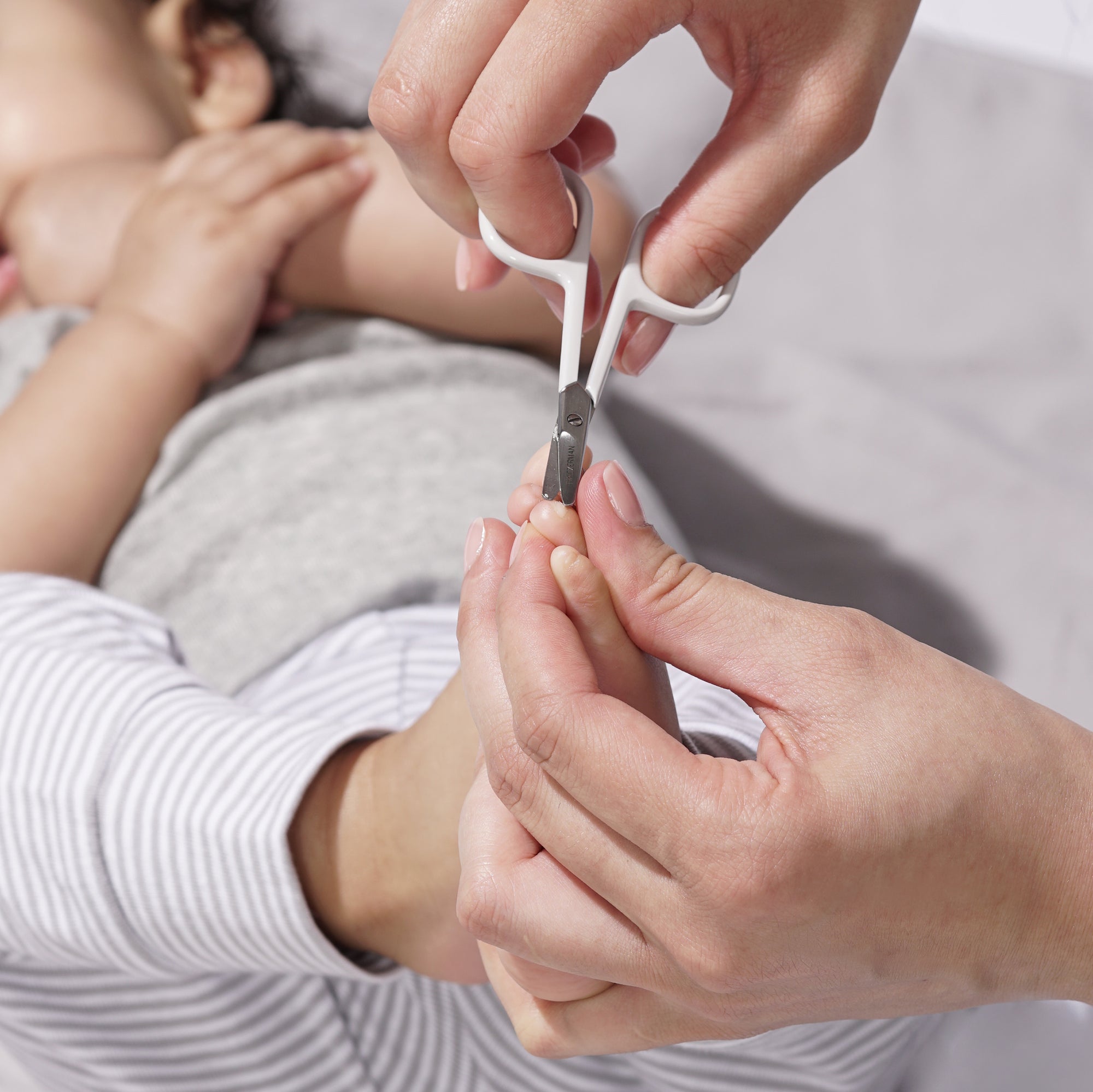 Model using Green Baby nail scissors on baby&#39;s feet