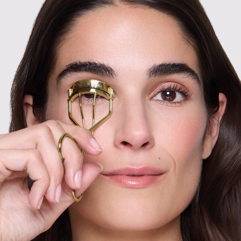 Model is curling her eyelashes with Evening Glow Lash Curler