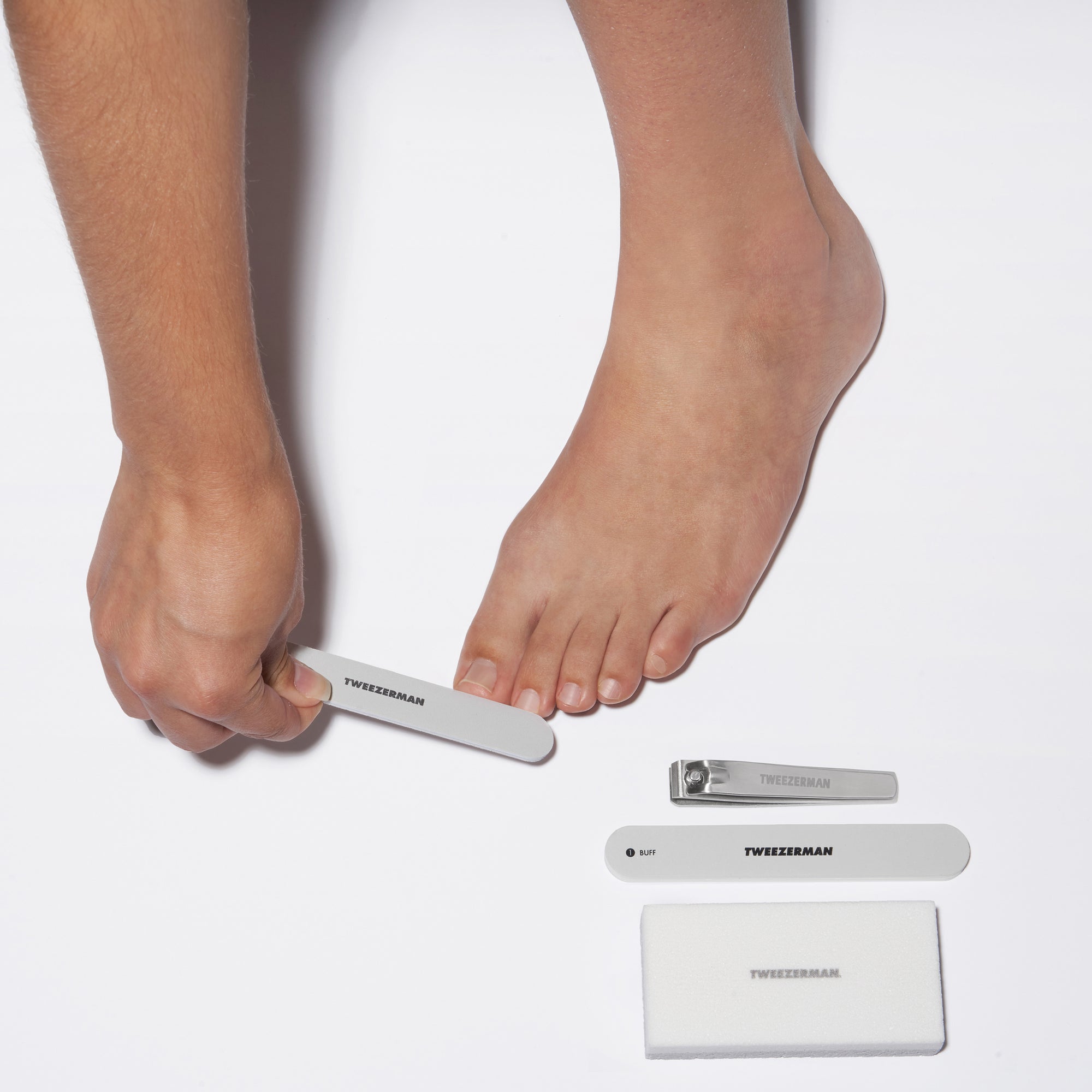 Model using Nail file with Toenail Clipper, Nail Buffer, and Pedicure stone on side.